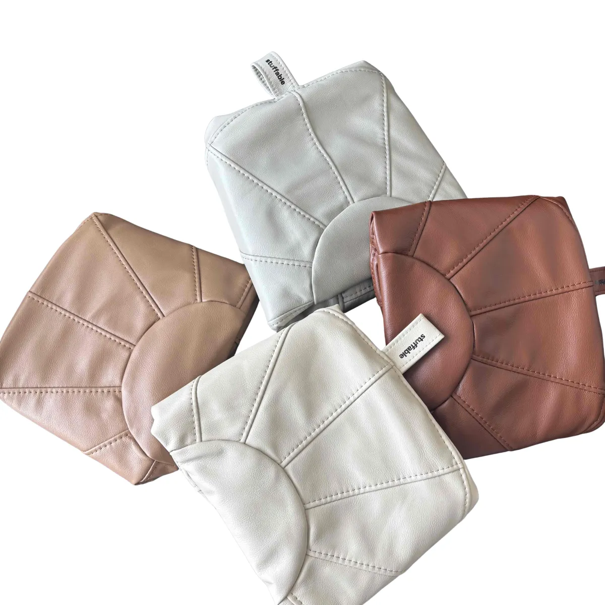 Four Stuffable pouf covers with the signature sunburst stitching, arranged in a cluster
